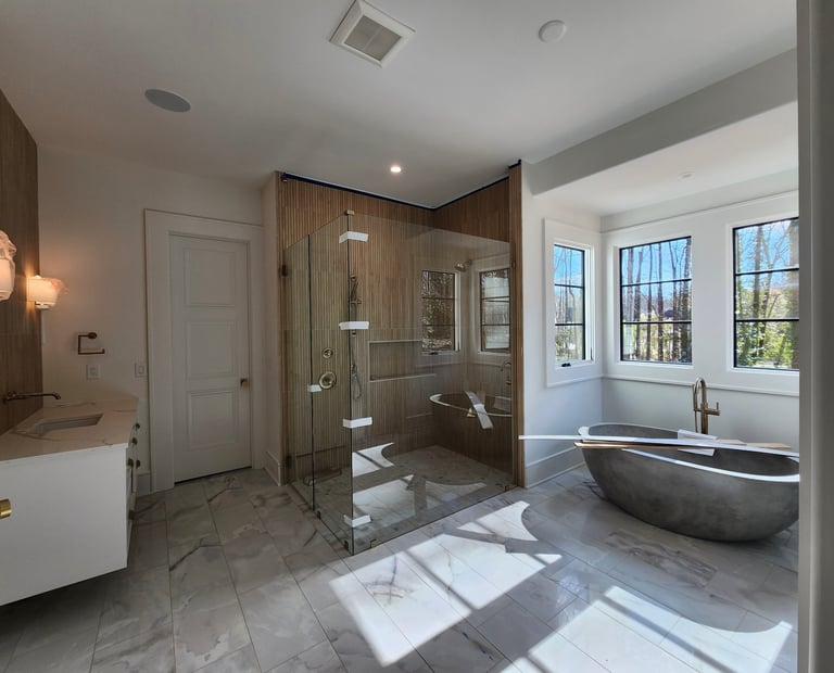 Modern luxury bathroom with large walk-in shower, freestanding soaking tub, marble flooring, and multiple windows with natural light