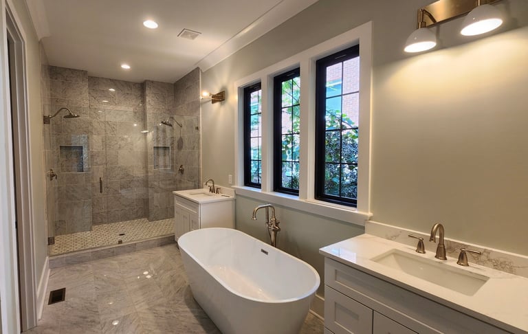 Modern luxury bathroom with freestanding oval bathtub, dual vanities, walk-in shower, and large windows